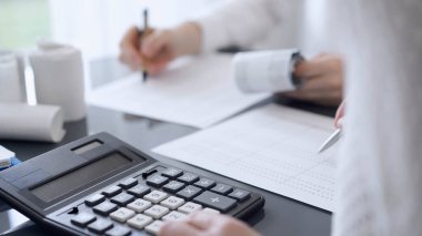 İki muhasebeci vergi veya gelir dengesi saymak için bir hesap makinesi ve dizüstü bilgisayar kullanıyor. İş, denetim ve vergi kavramları.