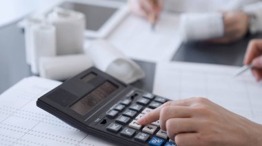 İki muhasebeci vergi veya gelir dengesi saymak için bir hesap makinesi ve dizüstü bilgisayar kullanıyor. İş, denetim ve vergi kavramları.