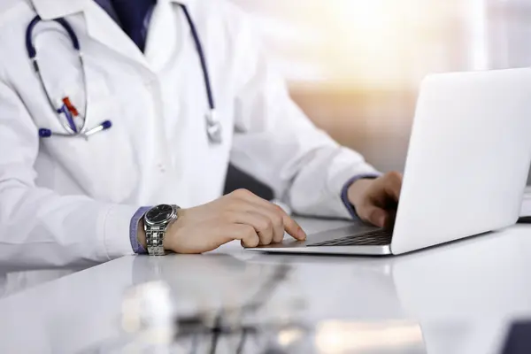 Unbekannter Arzt Sitzt Und Arbeitet Mit Laptop Abgedunkelter Klinik Hintergrund Stockbild