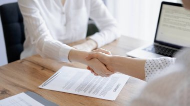 İş adamları kontrat kağıtlarının üzerinde el sıkışıyor. Tahta masaya yeni imzalanmış. Kapatın. Toplantıdaki avukatlar. Takım çalışması, ortaklık, başarı kavramı.