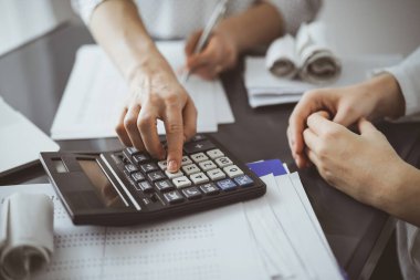 Müşteri için vergi sayarken hesap makinesi ve dizüstü bilgisayar kullanan kadın muhasebeci. İş denetimi ve finans kavramları.