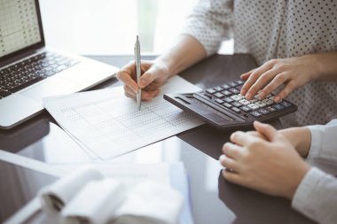 Müşteri için vergi sayarken hesap makinesi ve dizüstü bilgisayar kullanan kadın muhasebeci. İş denetimi kavramları.