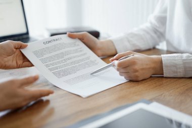 İş kadını avukat, ofisteki ahşap masada meslektaşı ya da müvekkili için bir şey itiraf eden özel sözleşmeye işaret ediyor. İş adamları takım çalışması ve ortaklık, toplantı konsepti.
