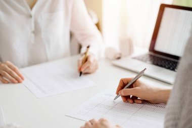 Beyaz masadaki vergileri saymak için dizüstü bilgisayar kullanan iki muhasebeci. İş denetimi ve finans alanında takım çalışması.