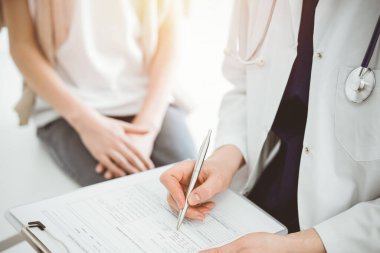 Doktor ve çocuk hasta. Hekim bir çocuğun yanında pano tutuyor ve tıbbi kayıt formunda yazıyor. Tıptaki ideal sağlık kavramı.
