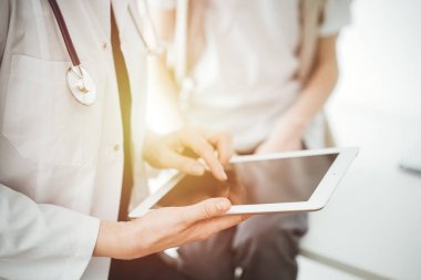 Doktor ve çocuk hasta. Doktor tablet bilgisayar kullanıyor ve çocuğu incelemeye hazır. Tıptaki ideal sağlık kavramı.