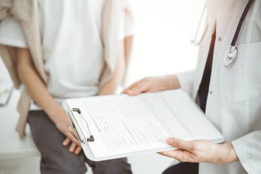 Doktor ve çocuk hasta. Hekim elinde bir çocuğun yanında ilaç geçmişi olan bir dosya tutuyor. Tıptaki ideal sağlık kavramı.