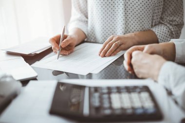 Müşteri için vergi sayarken hesap makinesi ve dizüstü bilgisayar kullanan kadın muhasebeci. İş denetimi ve finans kavramları.