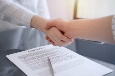 İş adamları sözleşme kağıtlarının üzerinde el sıkışıyorlar. Gri masaya yeni imzaladılar. Kapatın. Avukatlar ya da girişimciler toplantıda. Takım çalışması, ortaklık, başarı kavramı.