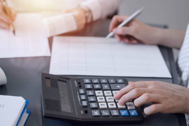 İki muhasebeci vergi veya gelir dengesi saymak için bir hesap makinesi ve dizüstü bilgisayar kullanıyor. İş, denetim ve vergi kavramları.