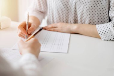 Ofisteki beyaz masada vergileri saymak için dizüstü bilgisayar ve hesap makinesi kullanan iki muhasebeci. İş denetimi ve finans alanında takım çalışması.