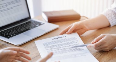 İş kadını avukat, ofisteki ahşap masada meslektaşı ya da müvekkili için bir şey itiraf eden özel sözleşmeye işaret ediyor. İş adamları takım çalışması ve ortaklık, toplantı konsepti.