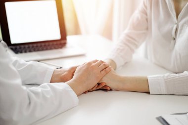 Doktor ve hasta klinikteki pencerenin yanındaki beyaz masada oturuyorlar. Kadın doktorların elleri güven veren kadınlarındır. Tıp konsepti.