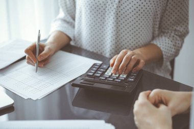 Müşteri için vergi sayarken hesap makinesi ve dizüstü bilgisayar kullanan kadın muhasebeci. İş denetimi ve finans kavramları.