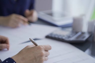 Ofisteki mali verileri inceleyen kadın muhasebeciler ya da denetçiler. Profesyoneller kağıt raporlarını inceliyor ve hesap makinesi kullanıyor, görüşü kapatıyor. Ticarette denetim ve vergiler.