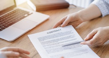 İş kadını avukat, ofisteki ahşap masada meslektaşı ya da müvekkili için bir şey itiraf eden özel sözleşmeye işaret ediyor. İş adamları takım çalışması ve ortaklık, toplantı konsepti.