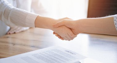 İş adamları kontrat kağıtlarının üzerinde el sıkışıyor. Tahta masaya yeni imzalanmış. Kapatın. Toplantıdaki avukatlar. Takım çalışması, ortaklık, başarı kavramı.