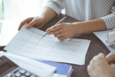 Denetim kağıdına kalemle işaret eden kadın muhasebeci vergi sayma sonuçlarını açıklarken, kapat. İş denetimi ve finans kavramları.