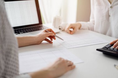 Ofisteki bir müşteriyle ya da meslektaşıyla vergi saymak için hesap makinesi ve dizüstü bilgisayar kullanan bir muhasebeci. İş denetimi ve finans alanında takım çalışması.