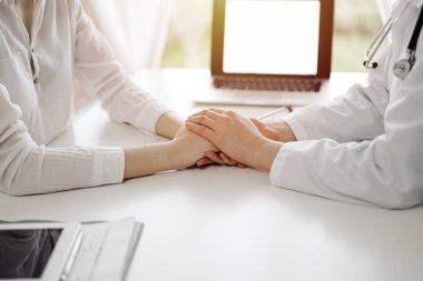 Doktor ve hasta klinikteki pencerenin yanındaki beyaz masada oturuyorlar. Kadın doktorların elleri güven veren kadınlarındır. Tıp konsepti.