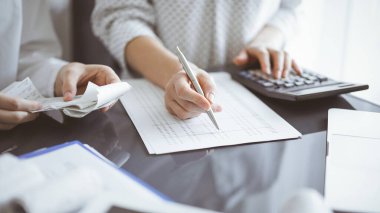 Müşteri ya da iş arkadaşıyla vergi sayarken hesap makinesi ve dizüstü bilgisayar kullanan kadın muhasebeci. İş denetleme ekibi.