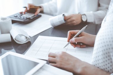 İki muhasebeci vergi veya gelir dengesi saymak için bir hesap makinesi ve tablet bilgisayar kullanıyor. İş, denetim ve vergi kavramları.