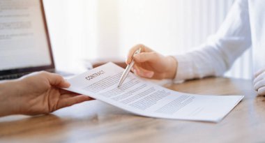 İş kadını avukat, ofisteki ahşap masada meslektaşı ya da müvekkili için bir şey itiraf eden özel sözleşmeye işaret ediyor. İş adamları takım çalışması ve ortaklık, toplantı konsepti.