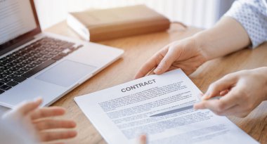 İş kadını avukat, ofisteki ahşap masada meslektaşı ya da müvekkili için bir şey itiraf eden özel sözleşmeye işaret ediyor. İş adamları takım çalışması ve ortaklık, toplantı konsepti.