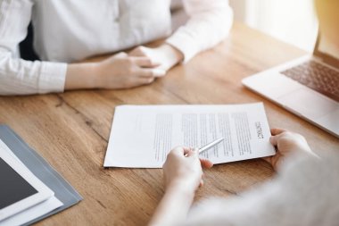 İş kadını avukat, ofisteki ahşap masada meslektaşı ya da müvekkili için bir şey itiraf eden özel sözleşmeye işaret ediyor. İş adamları takım çalışması ve ortaklık, toplantı konsepti.