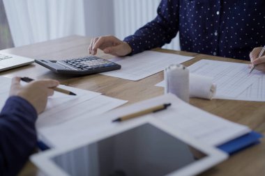 Accountants or auditors reviewing financial documents while sitting opposite one another at the wooden desk in office. Audit and taxes. clipart