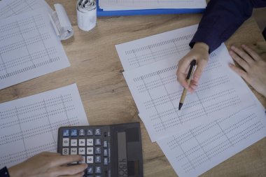 Accountants or auditors reviewing financial documents while sitting at the wooden desk in office, view above. Audit and taxes concept. clipart