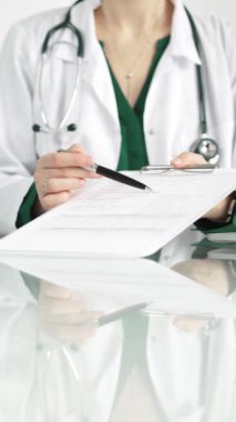 Hastane ortamındaki kadın doktor tıbbi raporlara işaret ediyor, yakın çekim çekimde uzmanlık gösteriyor. İlaç.