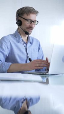 Erkek ofis çalışanı, modern iş dünyasındaki teknolojinin önemini dizüstü bilgisayar ve kulaklık kullanarak gösteriyor. İş adamları konsepti.