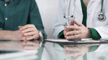 Tıbbi konsültasyon sırasında hastaya teşhis koyarken el kol hareketi yapan doktor, sağlık kararlarına destek ve rehberlik sunuyor..
