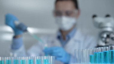 Laboratuvar tüpleri odaklandı, yakın görüş. Kadın araştırmacı, arka planda bir mikro pipet kullanıyor. Tıp ve bilim konsepti.