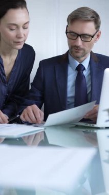 Modern ofis ortamında iş arkadaşları bir proje üzerinde çalışıyor, belgeleri analiz ediyor ve bir dizüstü bilgisayar kullanıyorlar. İş adamları konsepti.