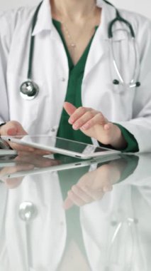 Modern sağlık ortamında dijital tablet kullanan beyaz önlüklü kadın doktor, hasta verileriyle etkileşime geçiyor..