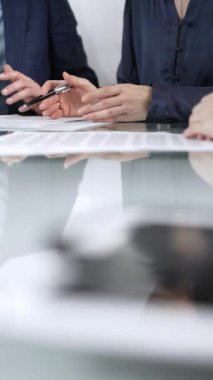 İş adamları bir toplantı sırasında sözleşme şartlarını gözden geçiriyorlar, müzakere ediyorlar ve birlikte kararlar veriyorlar, dikey yakın görüş. Boşluğu kopyala.