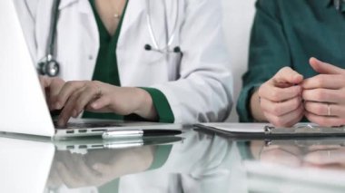 Kliniği, sağlık hizmetlerini ve tıbbi danışmanlık konseptini ziyaret eden bir hastaya dizüstü bilgisayarda muayene sonuçlarını gösteren kadın doktor.