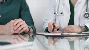 Doktor, klinikteki tıbbi danışmanlık sırasında hastanın şikayetlerini dinlerken panoya notlar yazıyor..