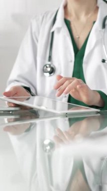 Modern sağlık ortamında dijital tablet kullanan beyaz önlüklü kadın doktor, hasta verileriyle etkileşime geçiyor..