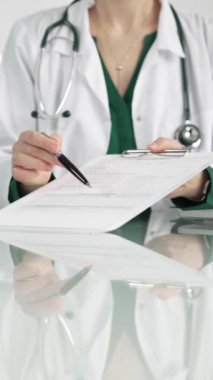 Hastane ortamındaki kadın doktor tıbbi raporlara işaret ediyor, yakın çekim çekimde uzmanlık gösteriyor. İlaç.