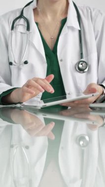 Modern sağlık ortamında dijital tablet kullanan beyaz önlüklü kadın doktor, hasta verileriyle etkileşime geçiyor..