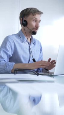 Erkek ofis çalışanı, modern iş dünyasındaki teknolojinin önemini dizüstü bilgisayar ve kulaklık kullanarak gösteriyor. İş adamları konsepti.