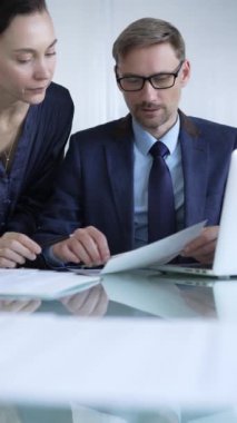 Modern ofis ortamında iş arkadaşları bir proje üzerinde çalışıyor, belgeleri analiz ediyor ve bir dizüstü bilgisayar kullanıyorlar. İş adamları konsepti.