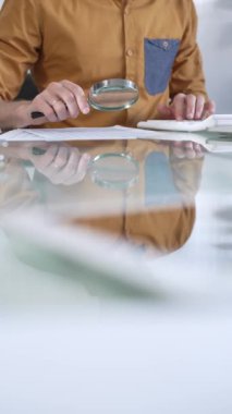 İş adamı muhasebeci gündelik sarı gömlekler giyiyor. Bütçe raporlarını dikkatle inceliyor. Ofiste büyüteç ve hesap makinesi var. Vergiler, iş denetimleri.