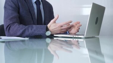 Mavi ceket giyen işadamı, modern bir ofisteki cam bir masadaki dizüstü bilgisayarla çevrimiçi iletişime odaklanarak üretkenlik ve konsantrasyon gösteriyor. İş veya denetim kavramı.