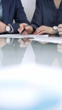 İş adamları bir toplantı sırasında sözleşme şartlarını gözden geçiriyorlar, müzakere ediyorlar ve birlikte kararlar veriyorlar, dikey yakın görüş. Boşluğu kopyala.