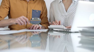 Ofislerinde mali denetim yapan iki muhasebeci bir büyüteç ve hesap makinesiyle belgeleri yakından inceliyor. Vergiler, iş denetimleri.