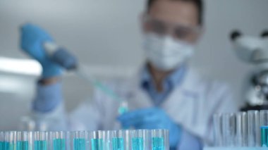 Laboratuvar tüpleri odaklandı, yakın görüş. Kadın araştırmacı, arka planda bir mikro pipet kullanıyor. Tıp ve bilim konsepti.